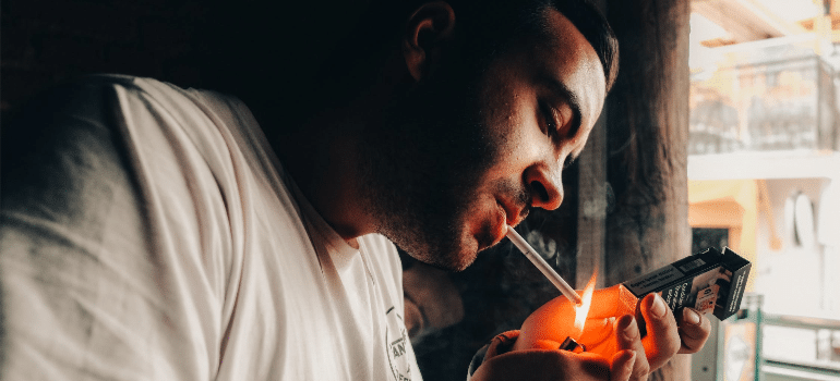 A man in a white shirt smoking a cigarette.