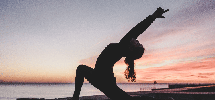 A silhouette of a woman doing yoga by the sea at prescription drugs addiction treatment in Palm Beach.