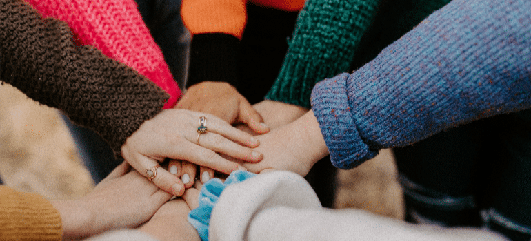 A close-up of people’s hands piled together in Boynton Beach prescription drugs addiction treatment center.