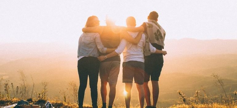 Four people hugging at sunset.
