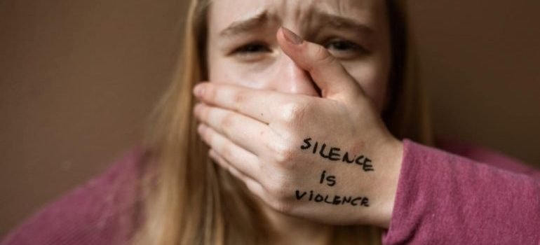 A sad woman with a hand over her mouth that has no freedom to say anything.