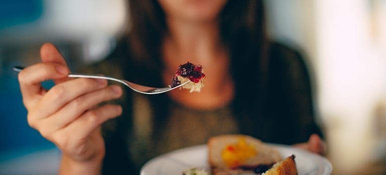 a woman taking a bite of cake and thinking about importance of nutrition in drug rehab