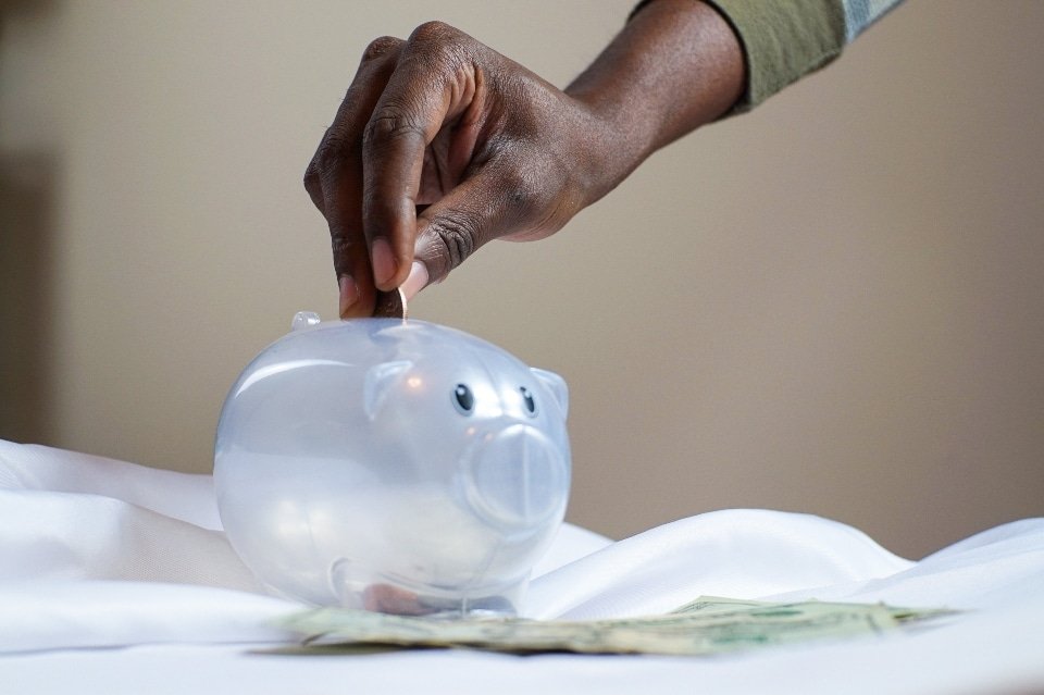 person putting a coin in a piggy bank to Financially Recover After Addiction