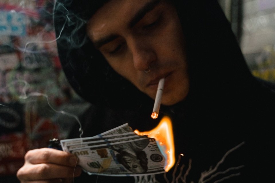 person showing the link between addiction and money problems by burning money