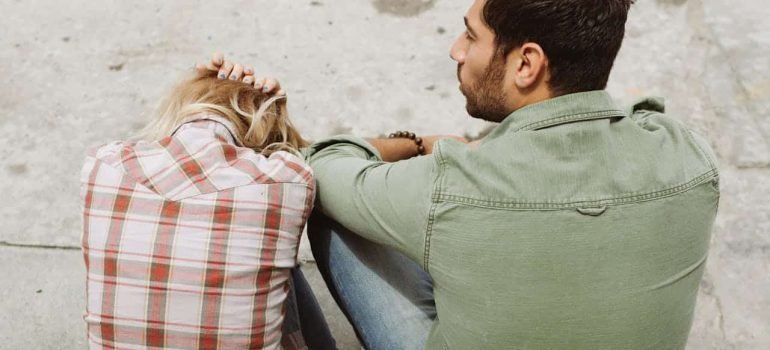 Man and Woman Sitting on Sidewalk