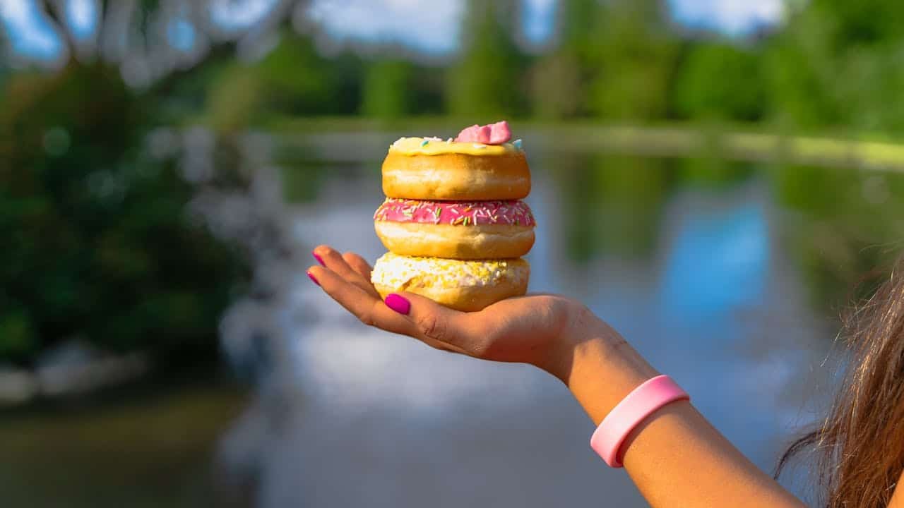 a woman holding three donuts because her brain is tricking her to want sugar during detox