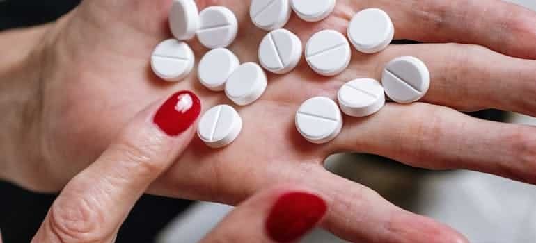 white pills in a lady's hand, mixing valium and alcohol