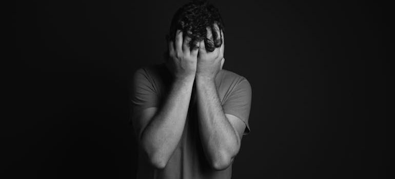 grayscale man holding face in hands
