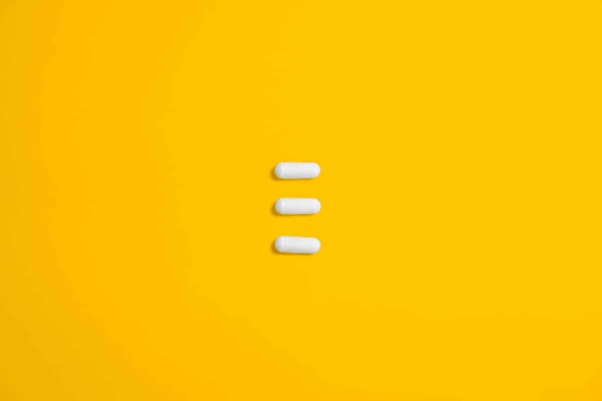 three pills on yellow background representing Vicodin abuse