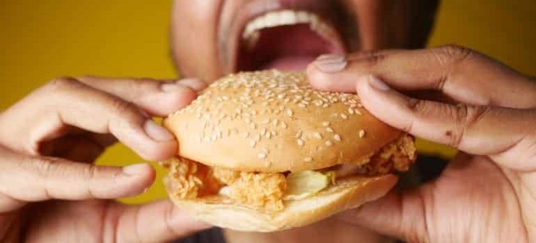 A man eating a burger, representing the role of balanced nutrition in restoring healthy sleep after Adderall use.